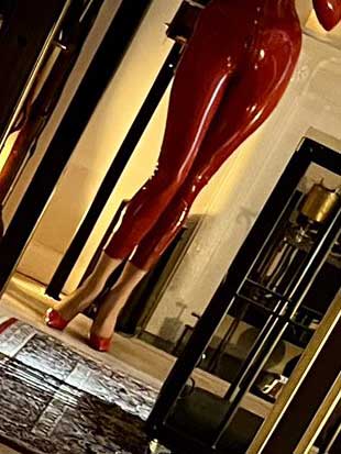 woman wearing red latex catsuit and patent red high heel shoes