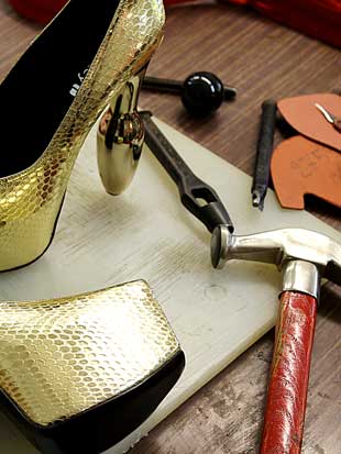 Golden high heels on artisan's workbench in Italian shoe factory